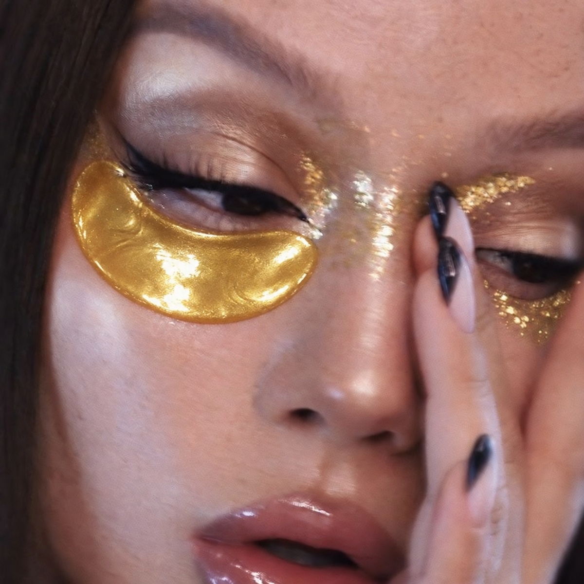 Gold under eye patches on model with gold glitter makeup