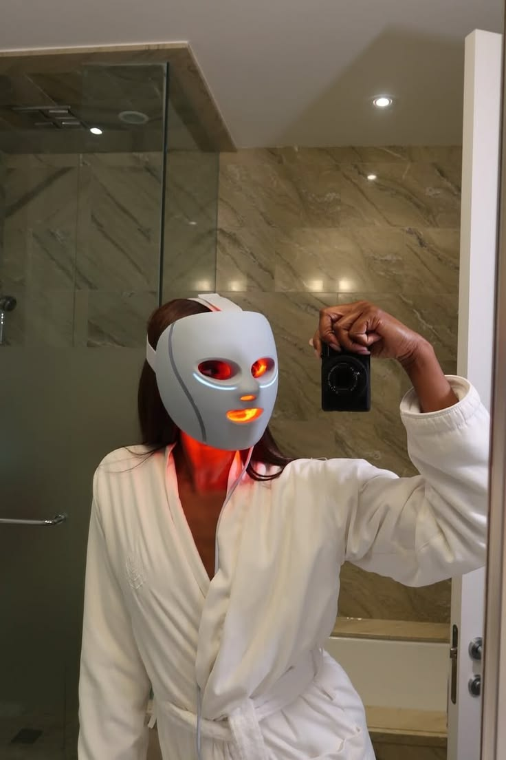 White LED face mask glowing red during a skincare routine