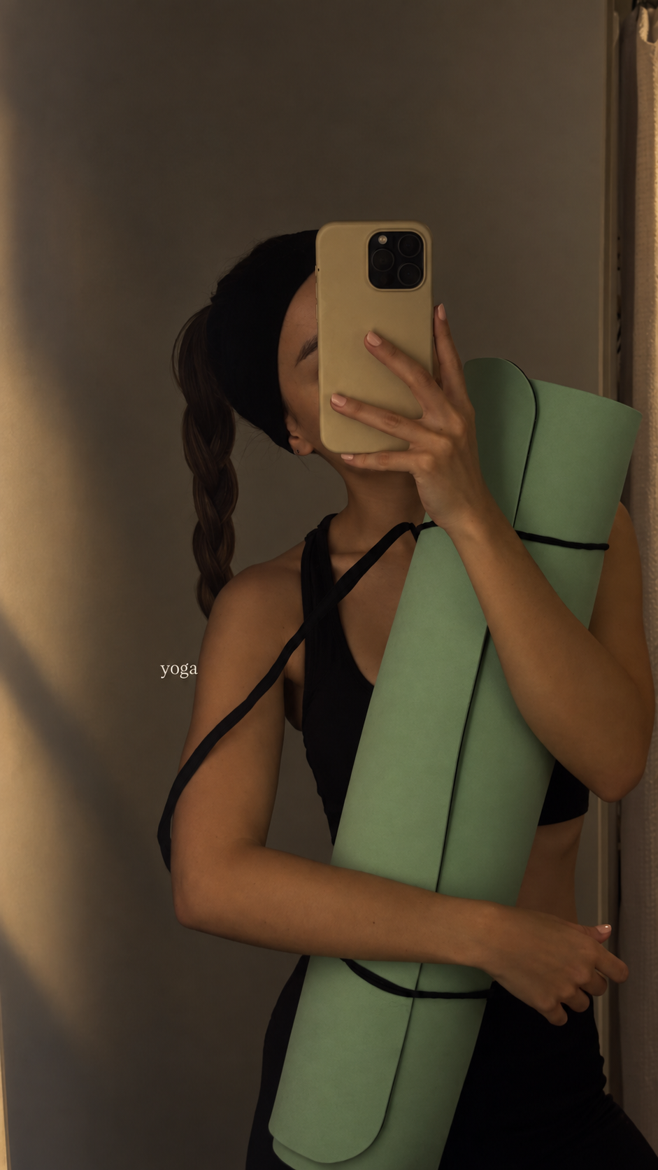 Woman holding a rolled green yoga mat