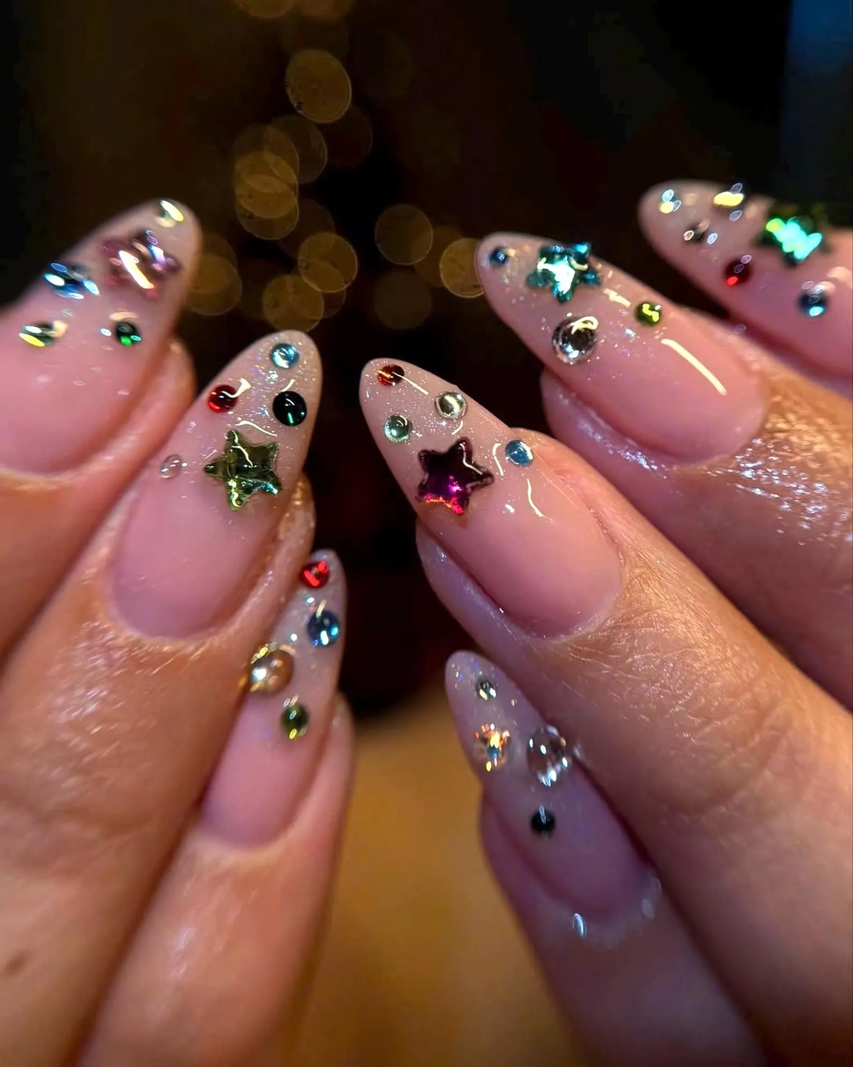 Colorful multi-shape rhinestones decorating pink nails
